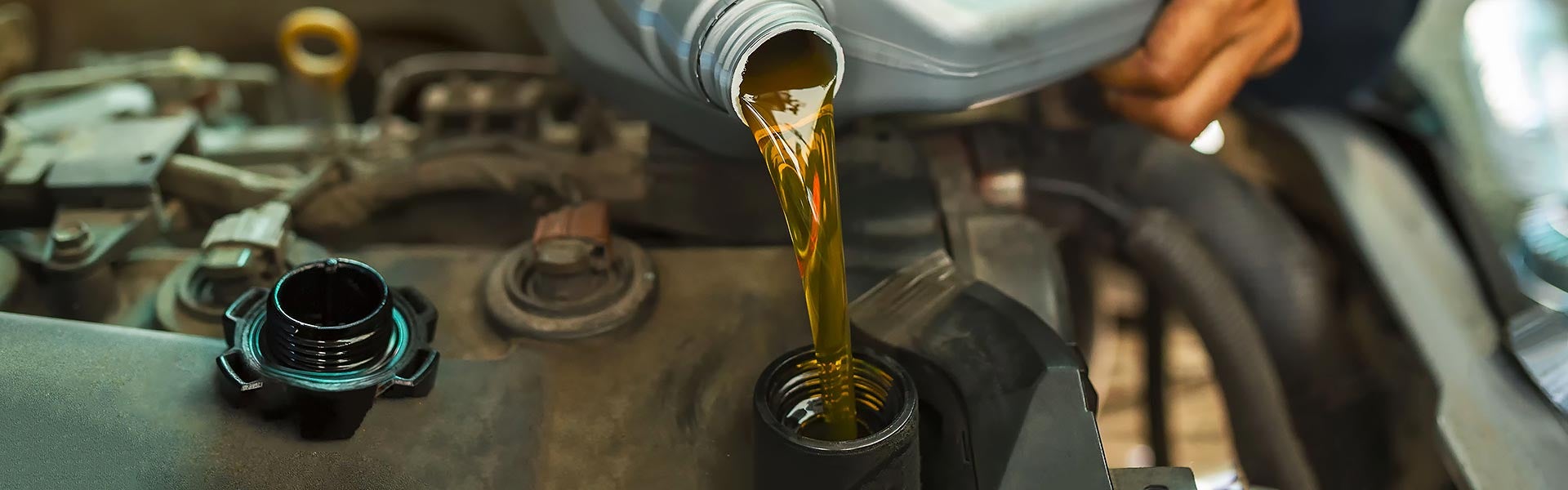 Motor oil being poured into a car engine during an oil change.